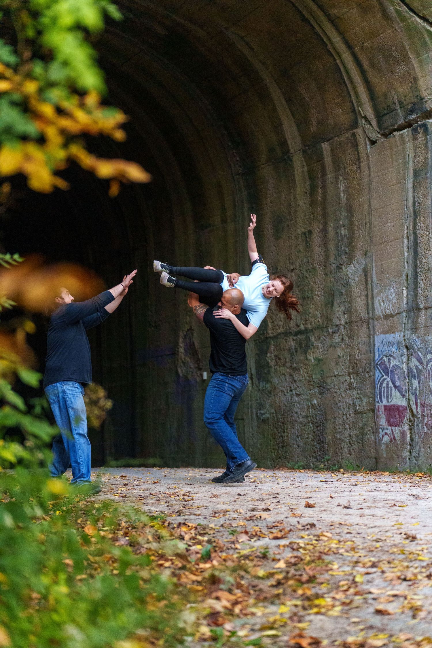 Sequence of dramatic poses against stone tunnel wall with autumn leaves.