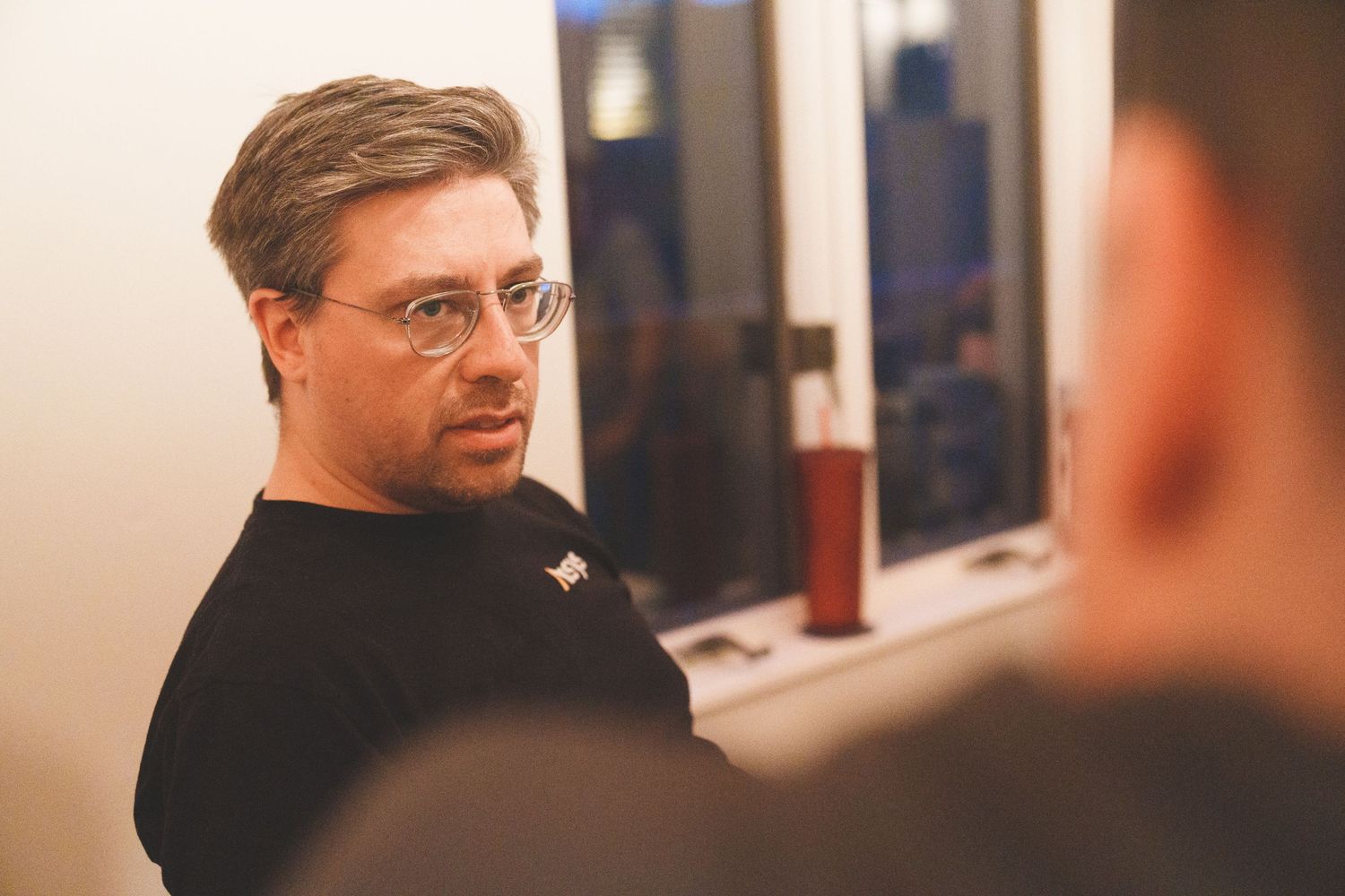 Person in black shirt looking over their shoulder in an office setting.