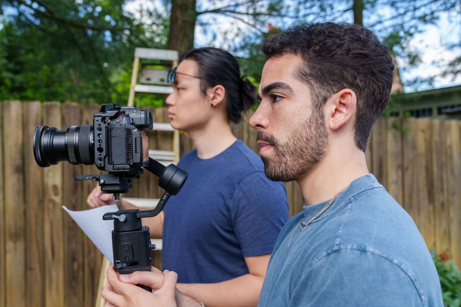 Several photographers with professional cameras shooting outdoors in a backyard setting.