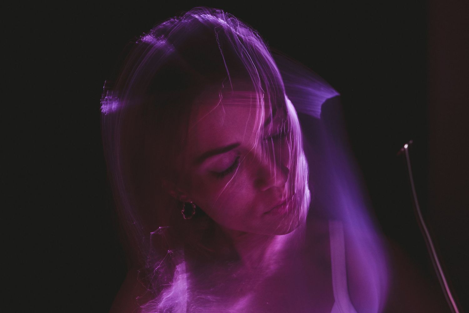 Swirling purple light trails form mystical shapes in darkness.