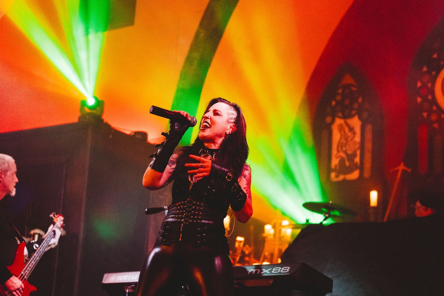Colorful stage performance with vibrant green and orange lighting creating dramatic atmosphere during live show.