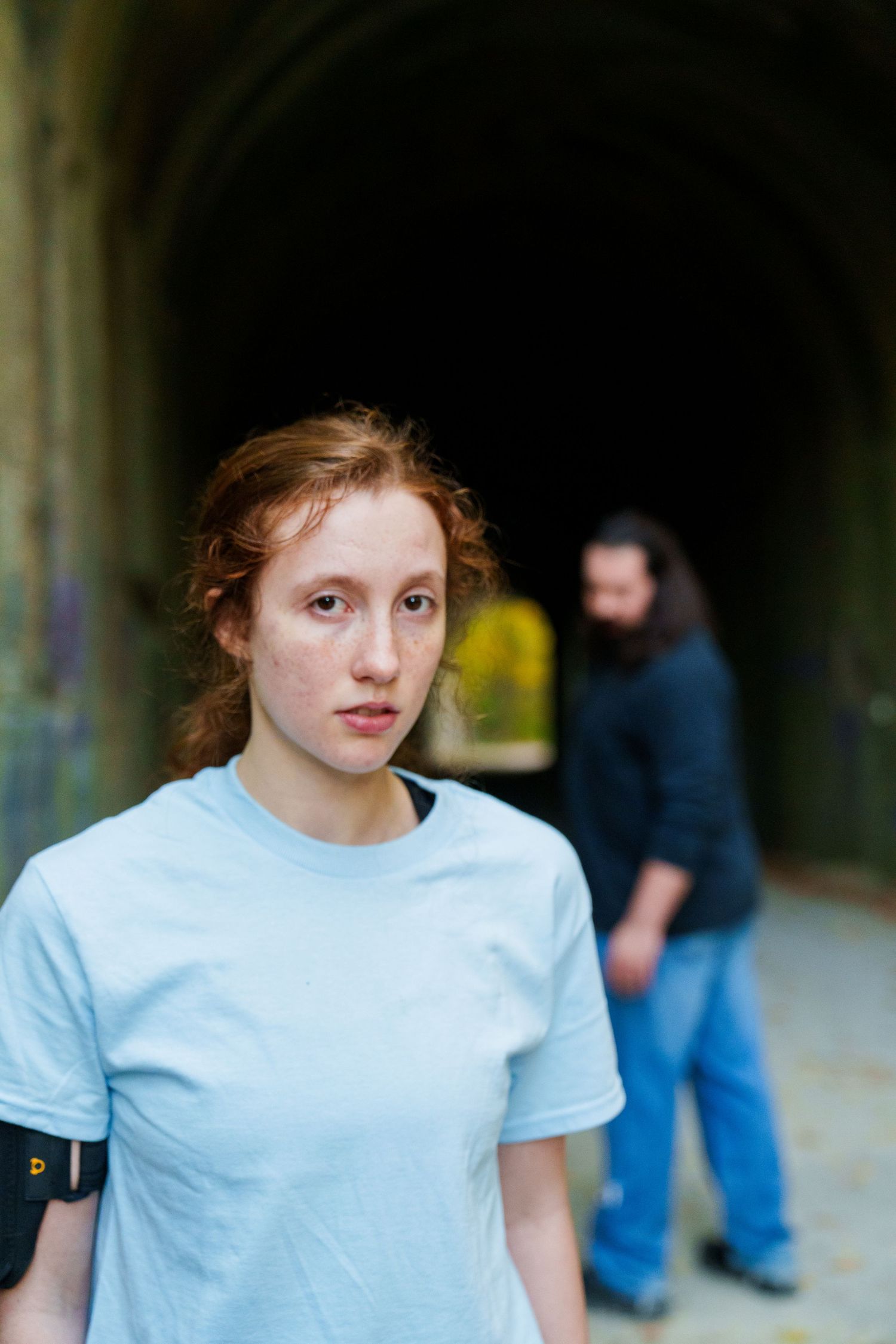 Person in white t-shirt standing against dark tunnel background.