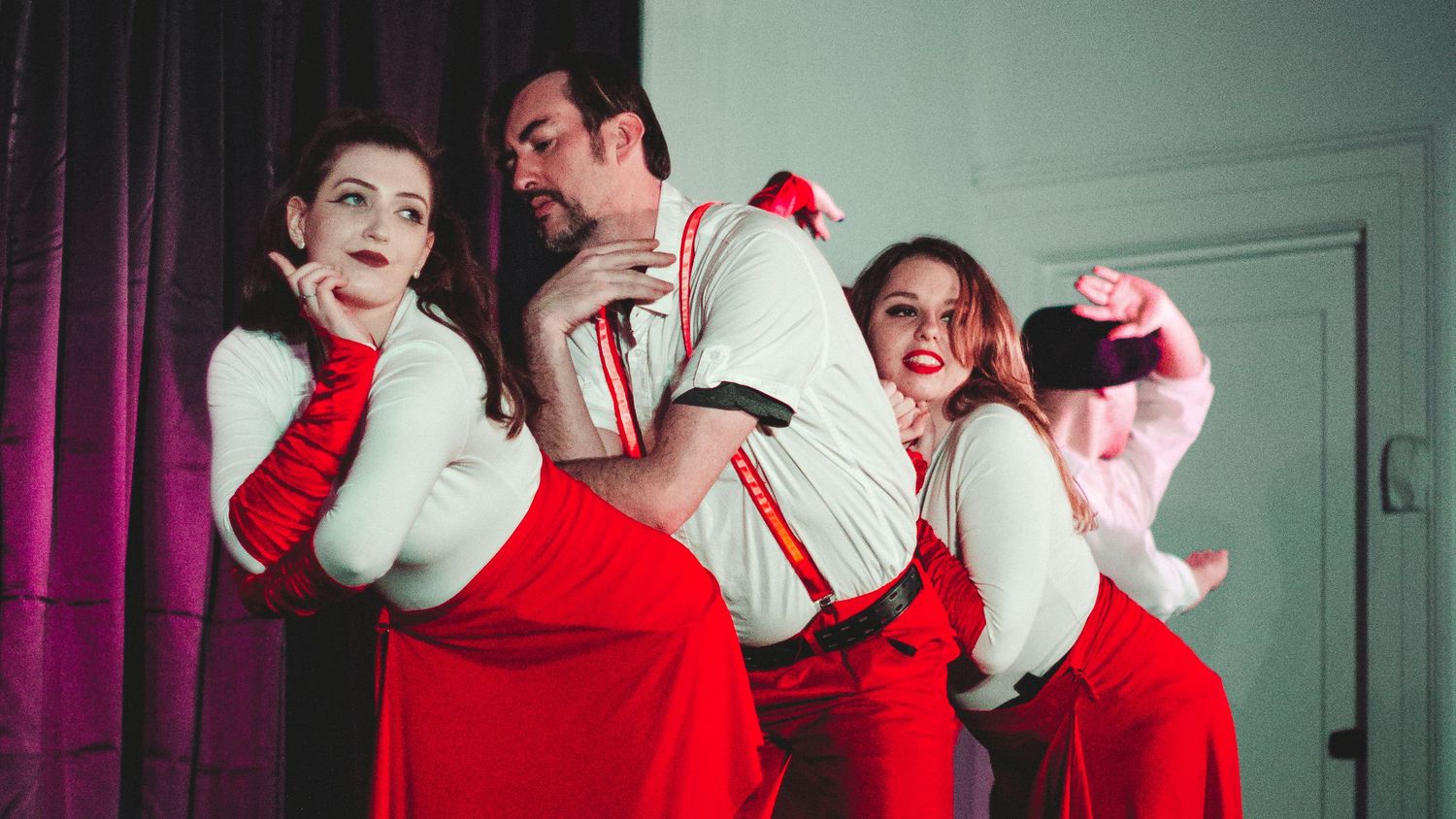Theatrical scene with performers in red and white costumes on stage.