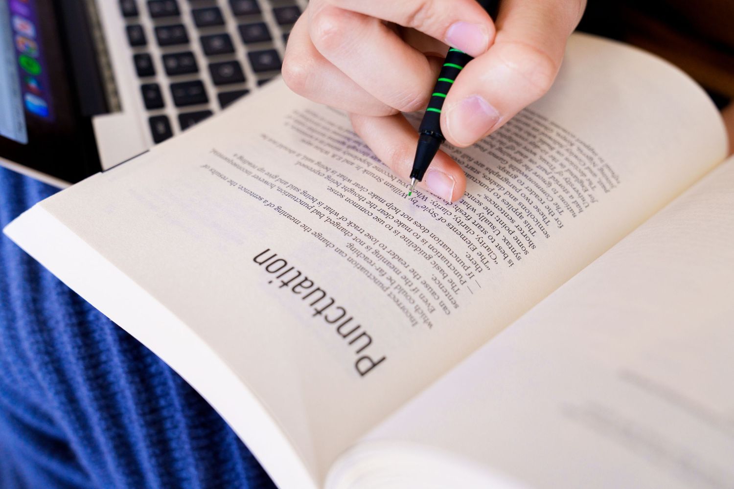 Close-up of hand highlighting text in an open book.