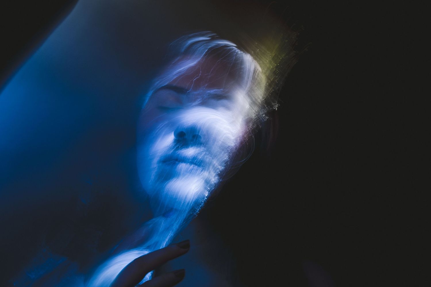 Abstract blue light trails against black background creating ethereal movement patterns.