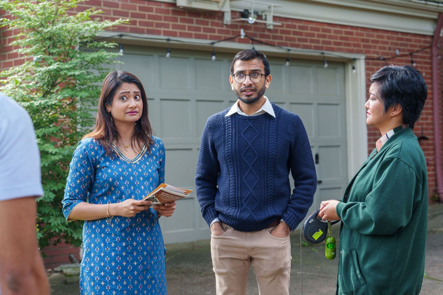People having an animated conversation outside a residential building with brick walls.