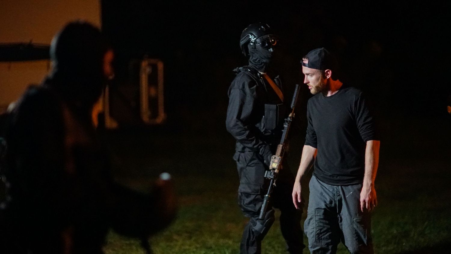 Dark dramatic scene with figures in tactical gear at night.