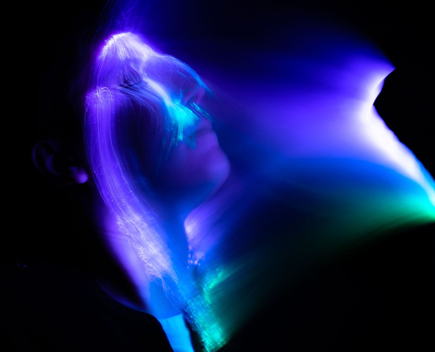 Purple and blue light trails swirling in an abstract pattern on black background.