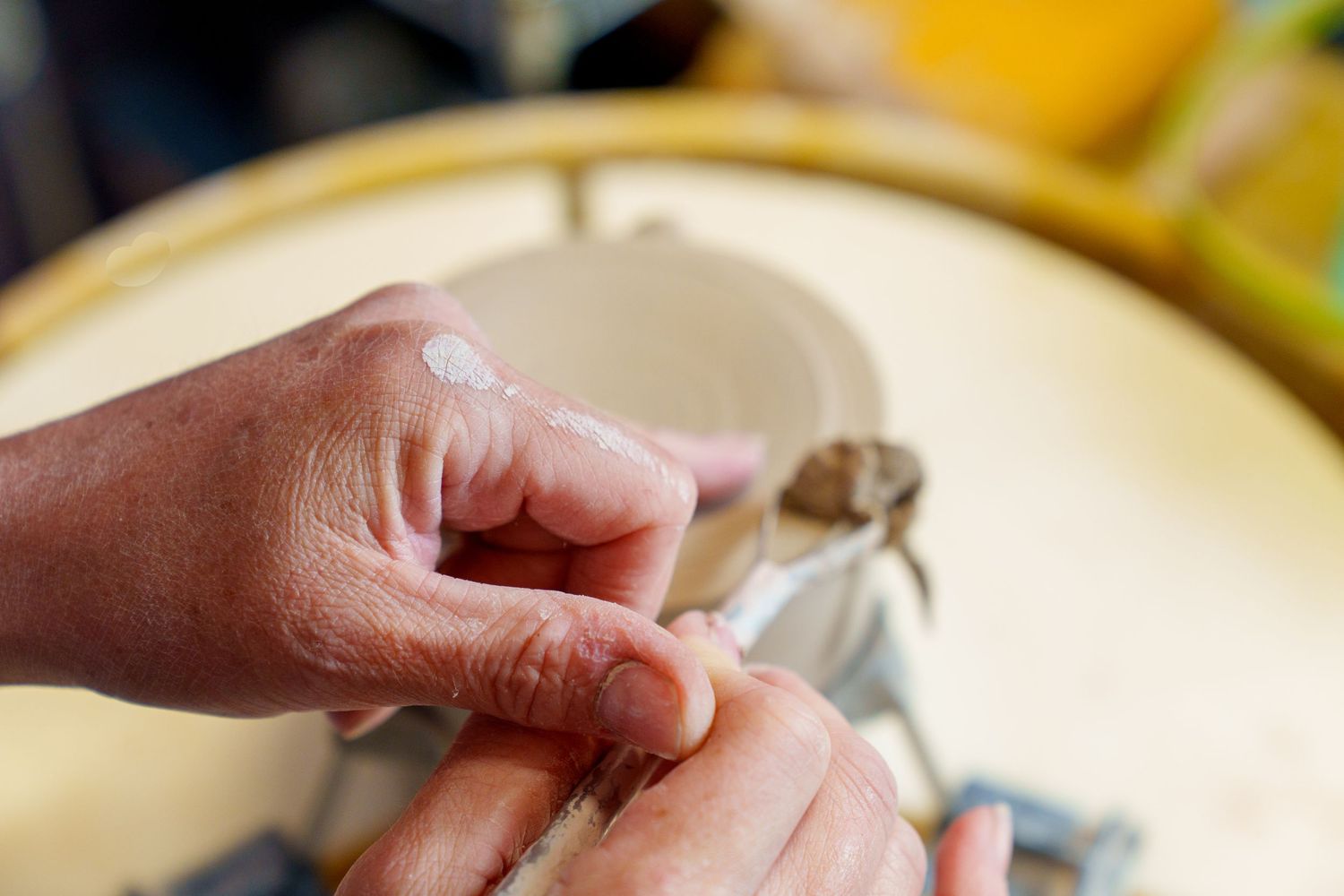 Hands preparing dough by kneading and folding it on a floured wooden surface.