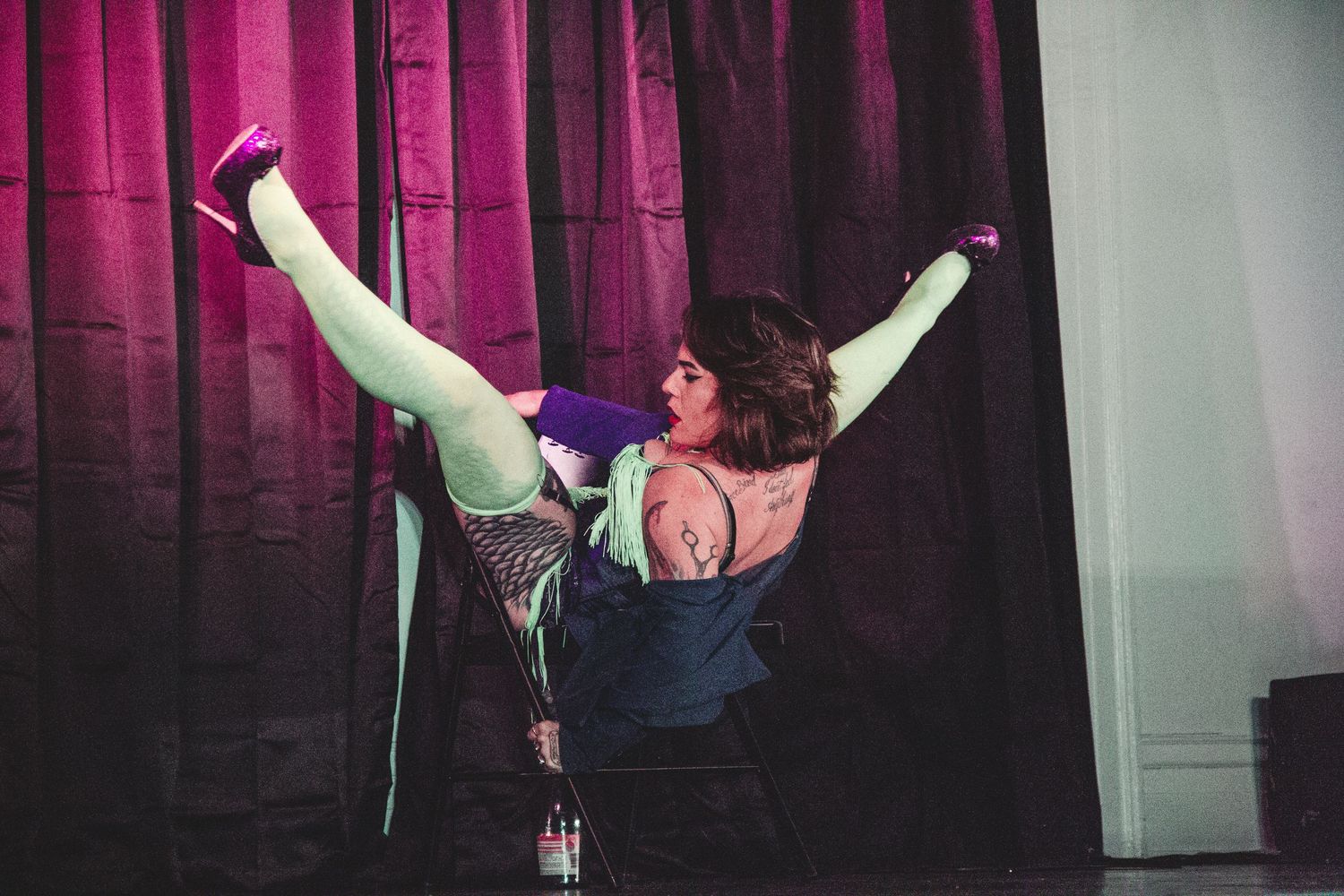 Dramatic stage performance with performers in black against purple curtain backdrop.