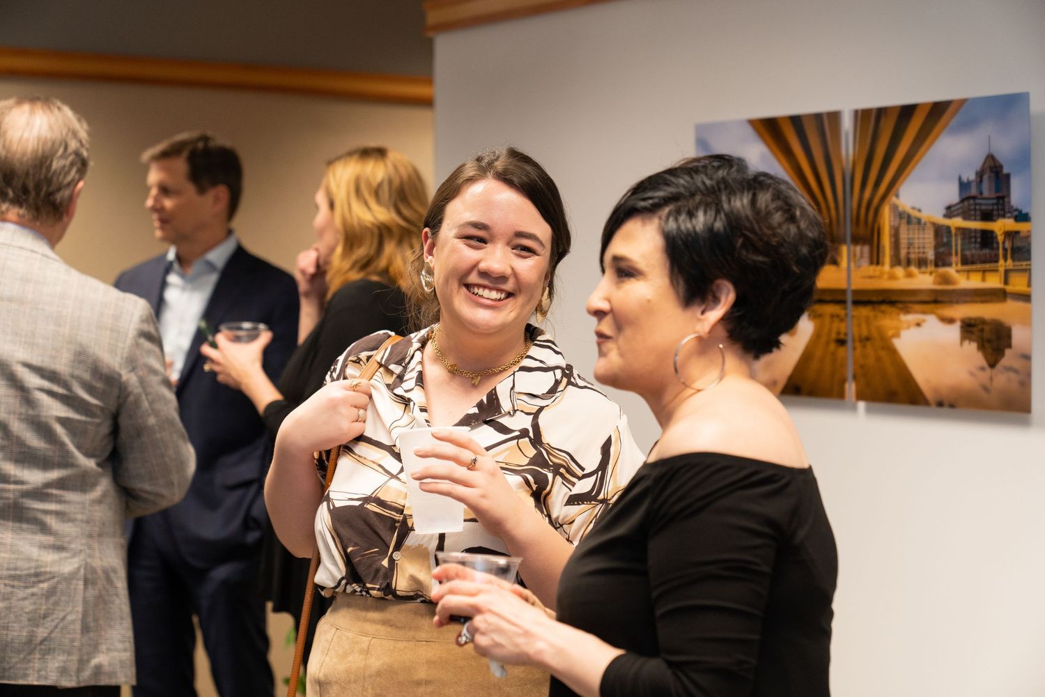 People enjoying conversation at an art gallery reception event.