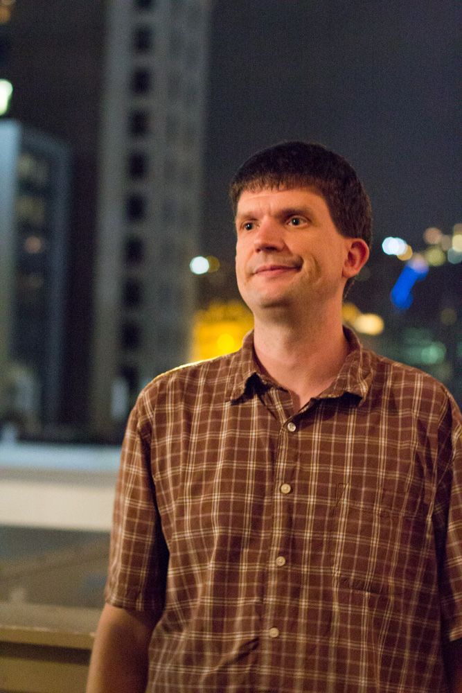 A sequence of five photos showing someone in a plaid shirt smiling against a dark urban background at night.