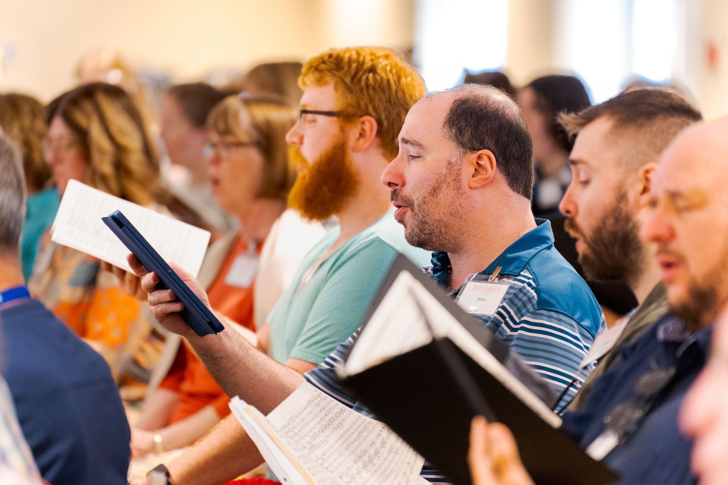 A group of choir singers reading sheet music during a choral performance or rehearsal.