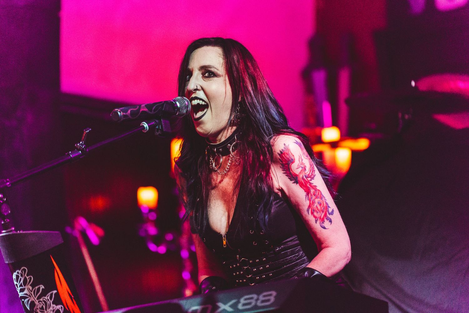 Rock musician performs passionately on stage with dramatic pink and red lighting effects.