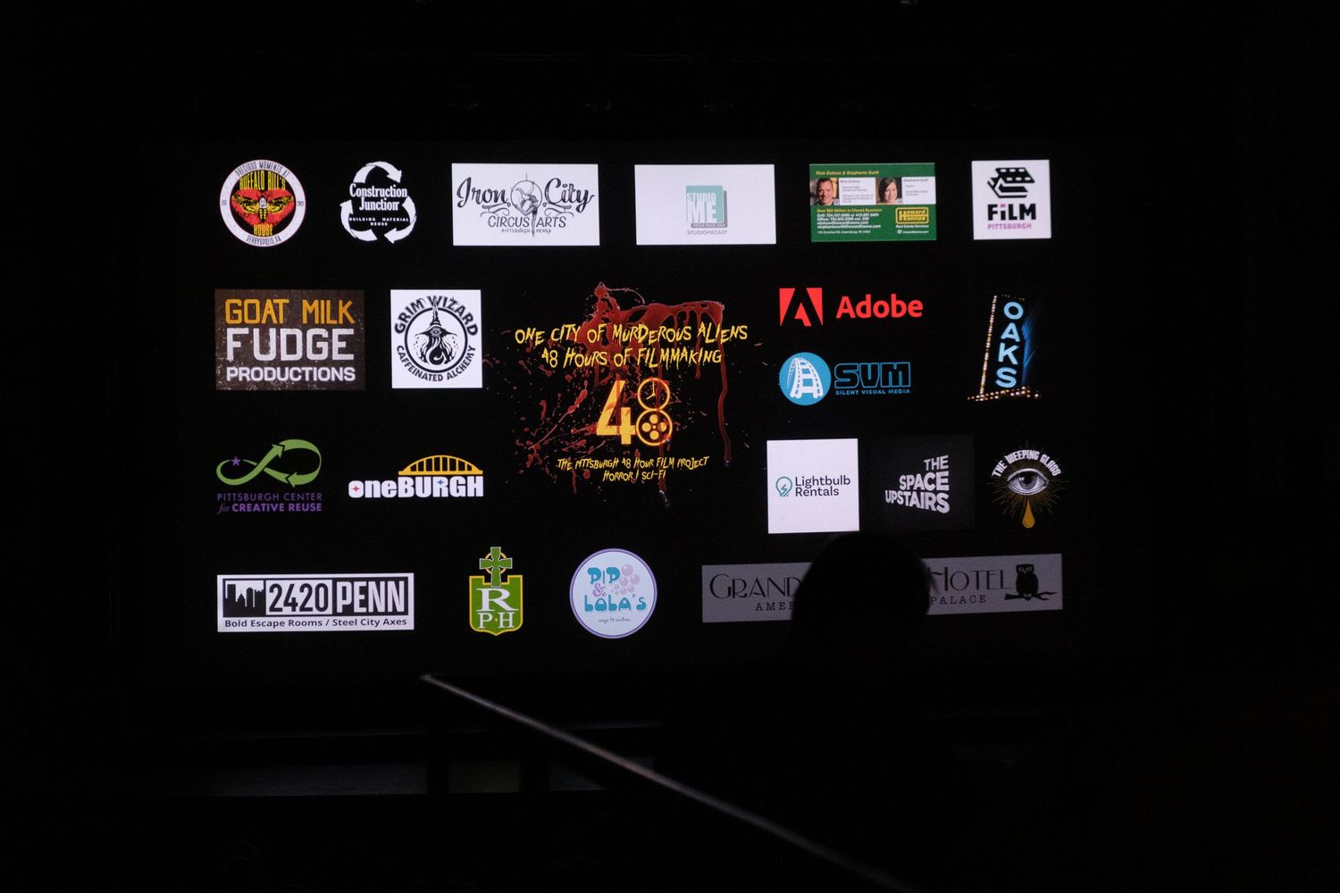 Row of sponsor logos and brand icons displayed on black background at an event.