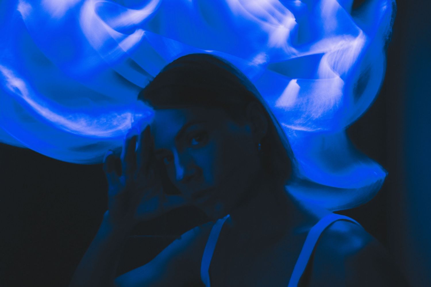Flowing blue smoke or light creates ethereal waves against black background.