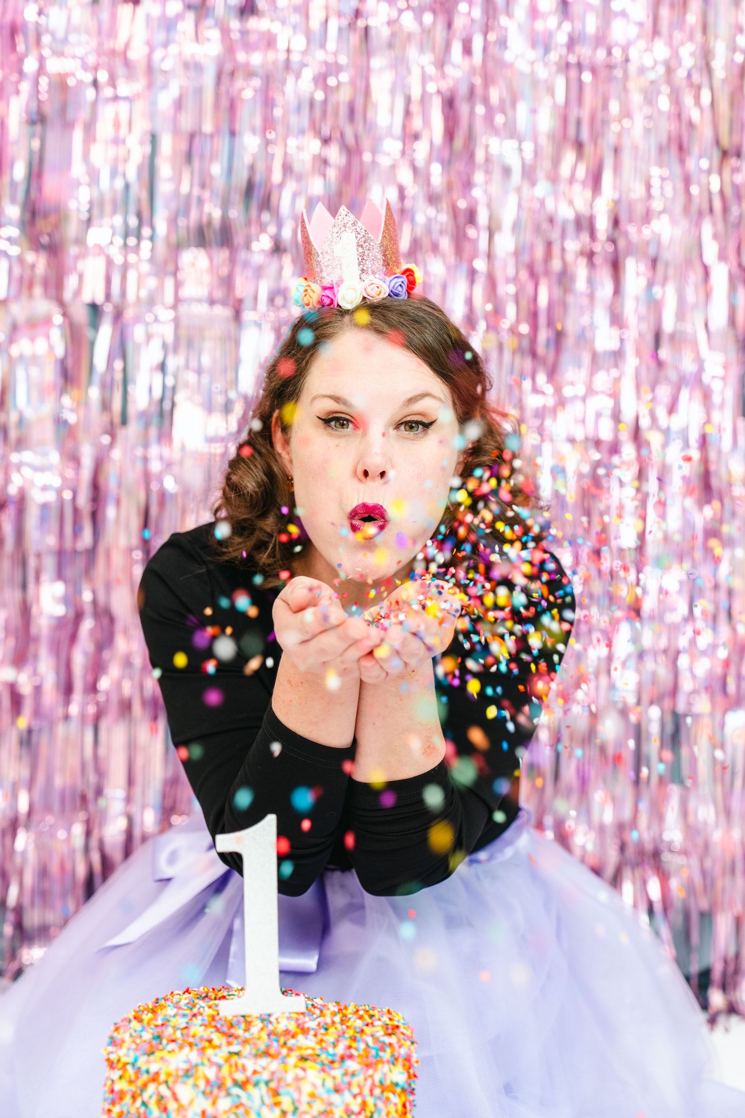 Festive celebration with confetti against pink tinsel backdrop.