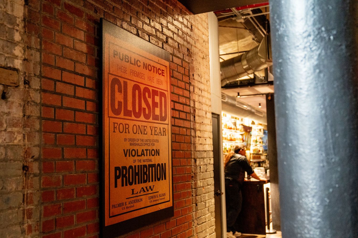 Vintage Prohibition-era closed notice sign on brick wall in dimly lit bar corridor.