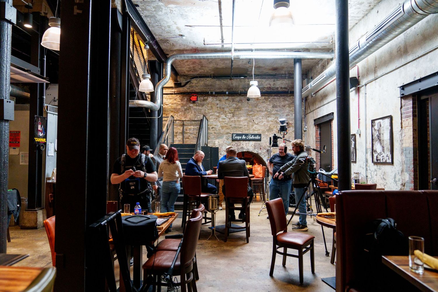 Hip cafe interior with exposed brick walls and industrial design features filled with patrons enjoying drinks and conversation.