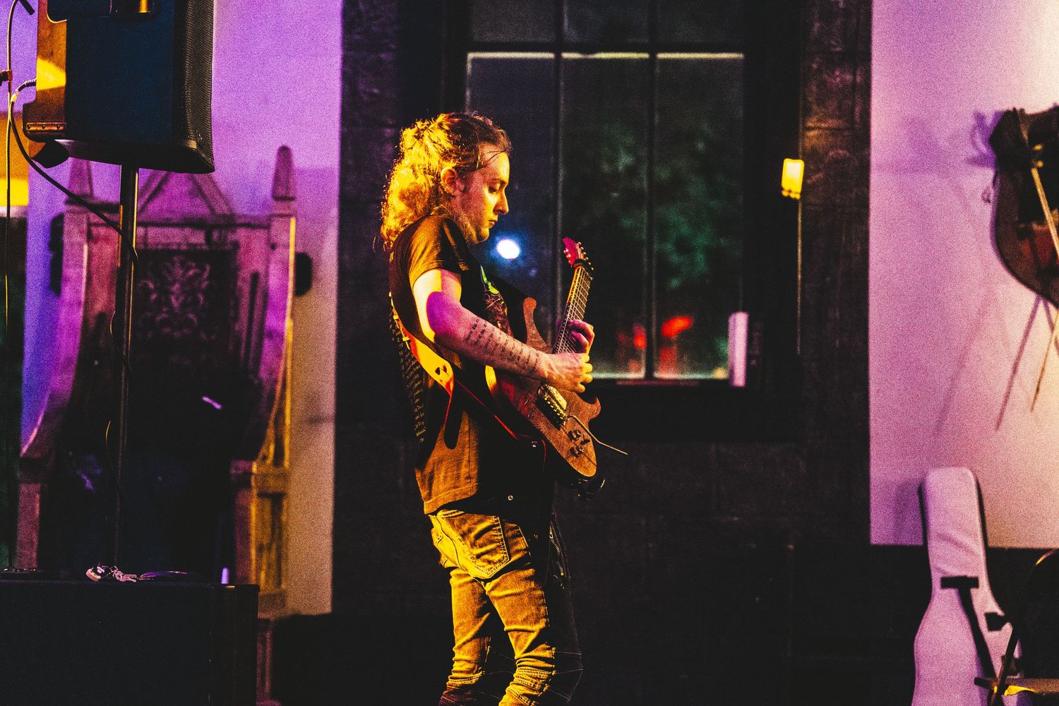 Dynamic concert scene with performers silhouetted against purple stage lighting and theatrical effects.