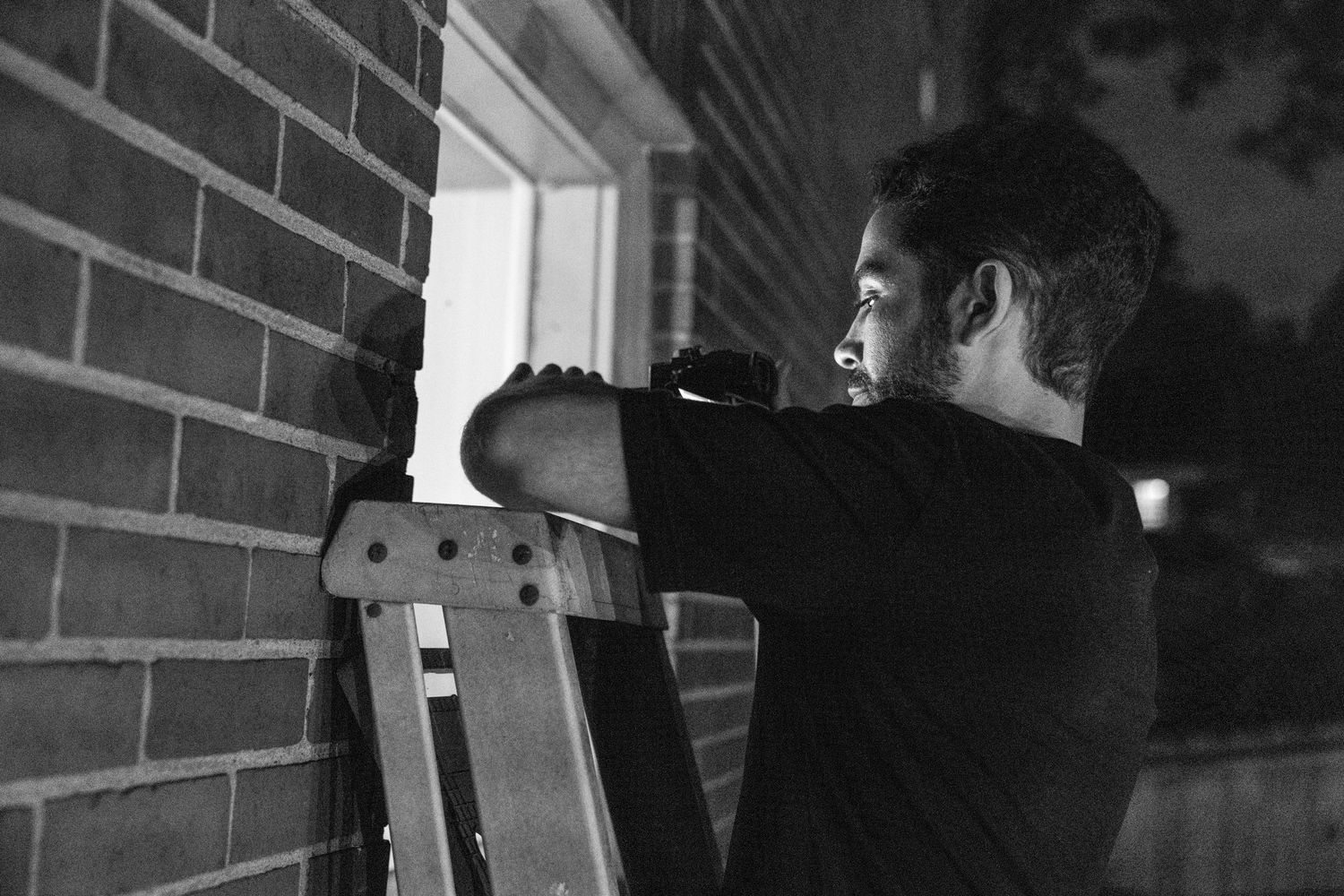 Dark moody portrait series with dramatic side lighting against brick wall.