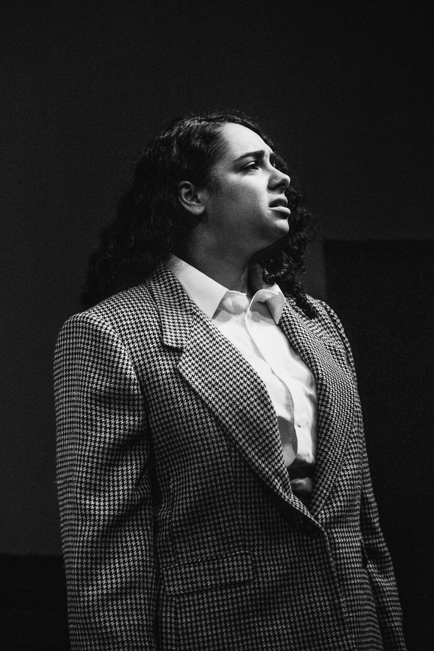 Dramatic black and white photos showing performer in checkered suit jacket during emotional scene.
