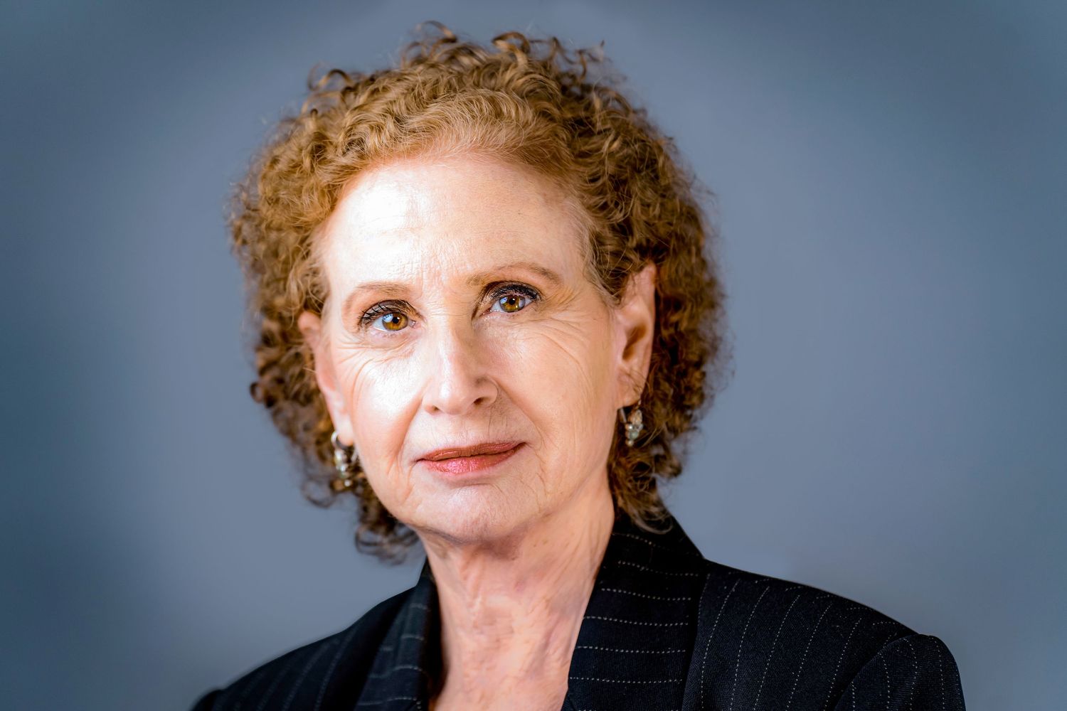 A series of headshots showing different expressions and angles of a person with curly red hair against a blue background.