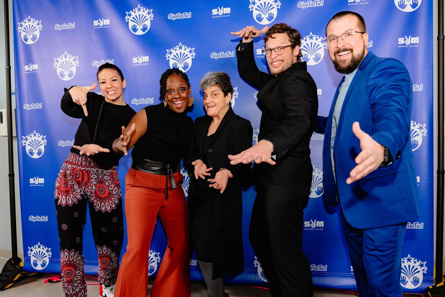 Group of people posing together on a blue carpet at an entertainment industry event.