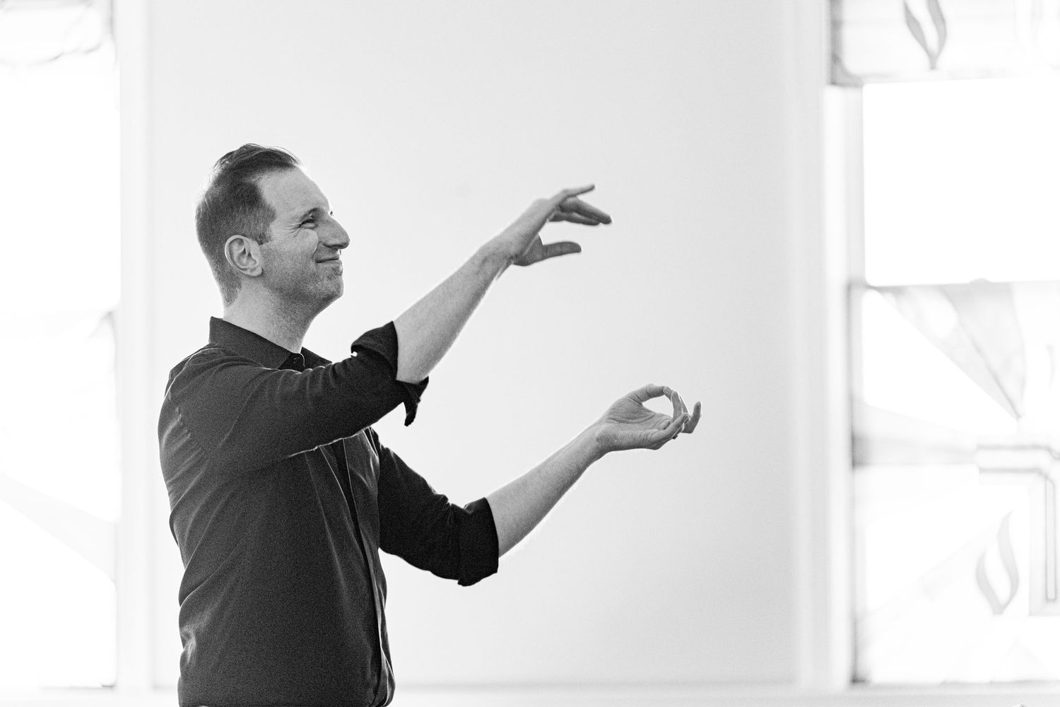 Silhouetted figure making expressive gestures against white background.