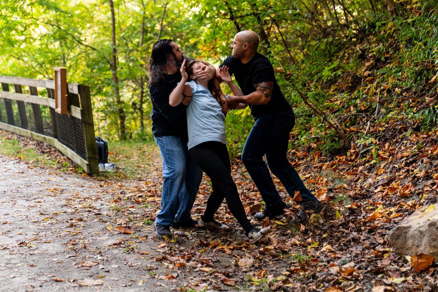 Group practicing stage combat moves in wooded outdoor setting.