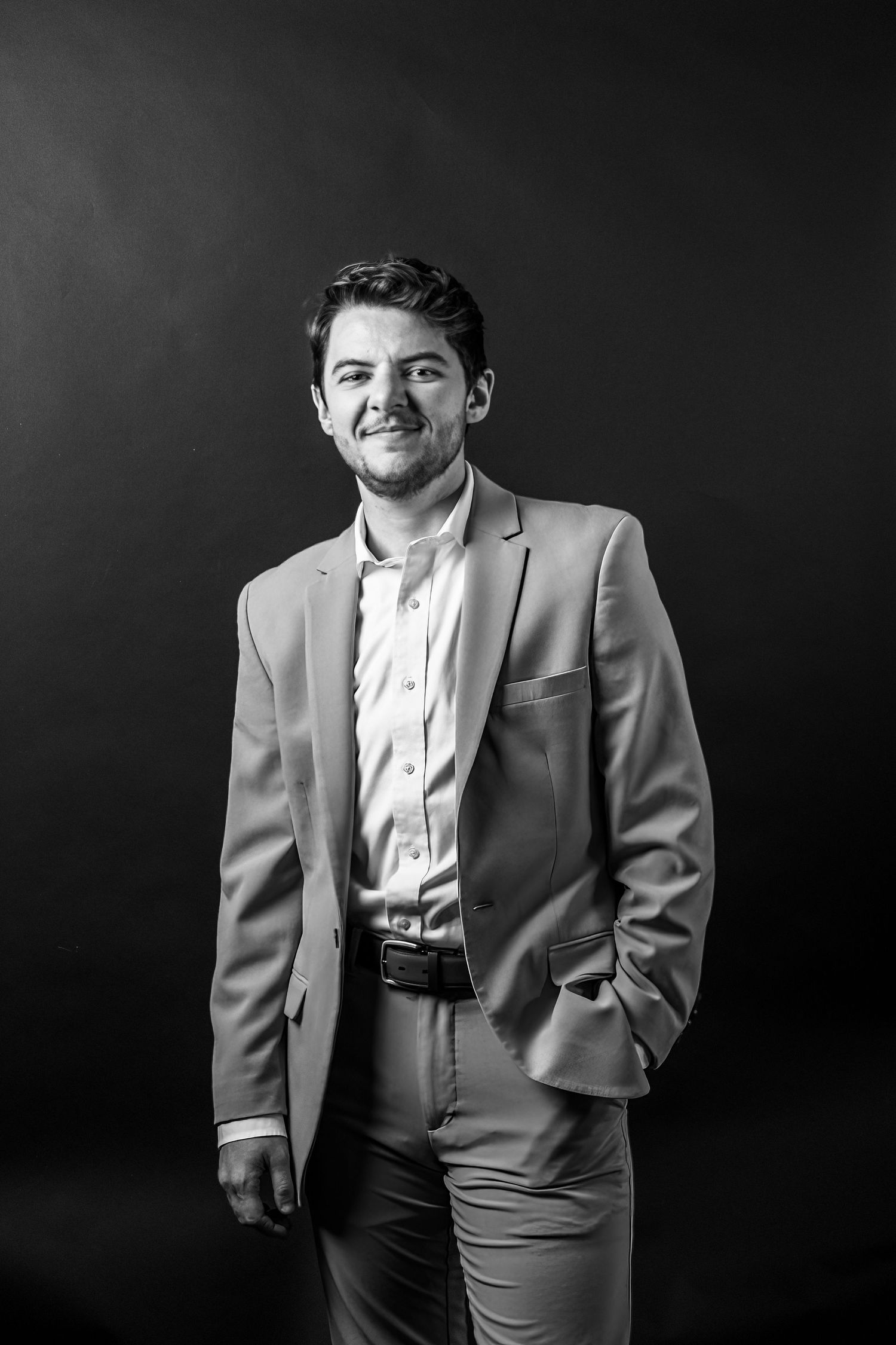 Black and white portrait series shows someone in a light colored suit jacket against a dark background.
