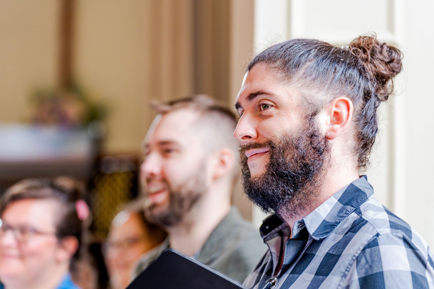 Audience members watching and smiling during an indoor event.