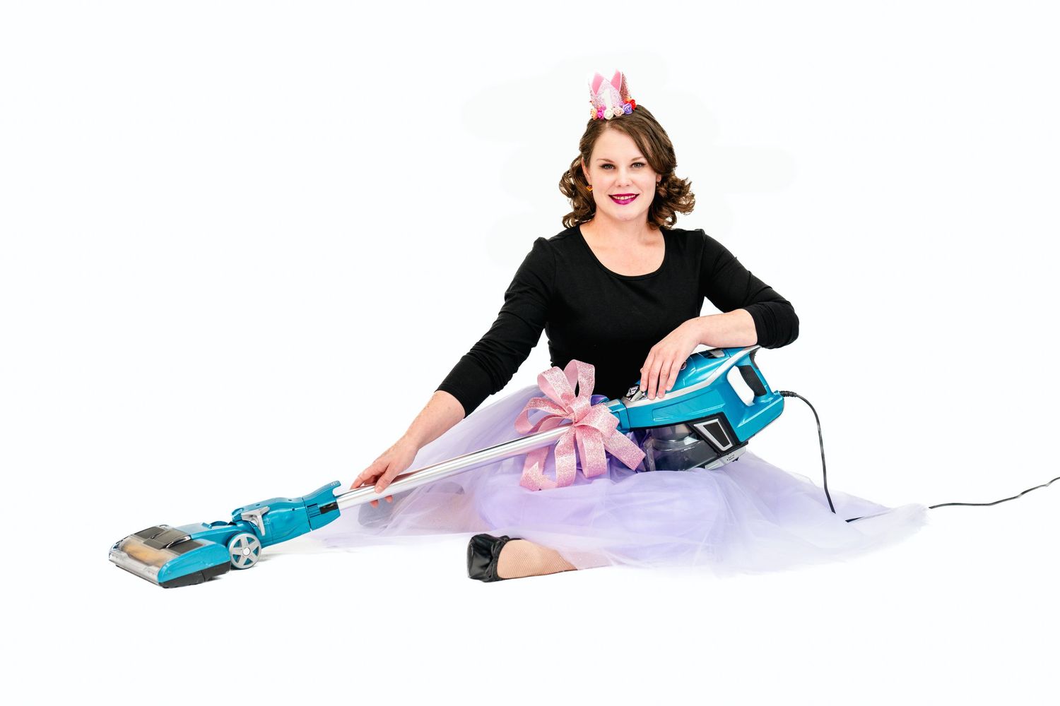 Stylish pose with vacuum cleaner while wearing purple tulle skirt and black top.
