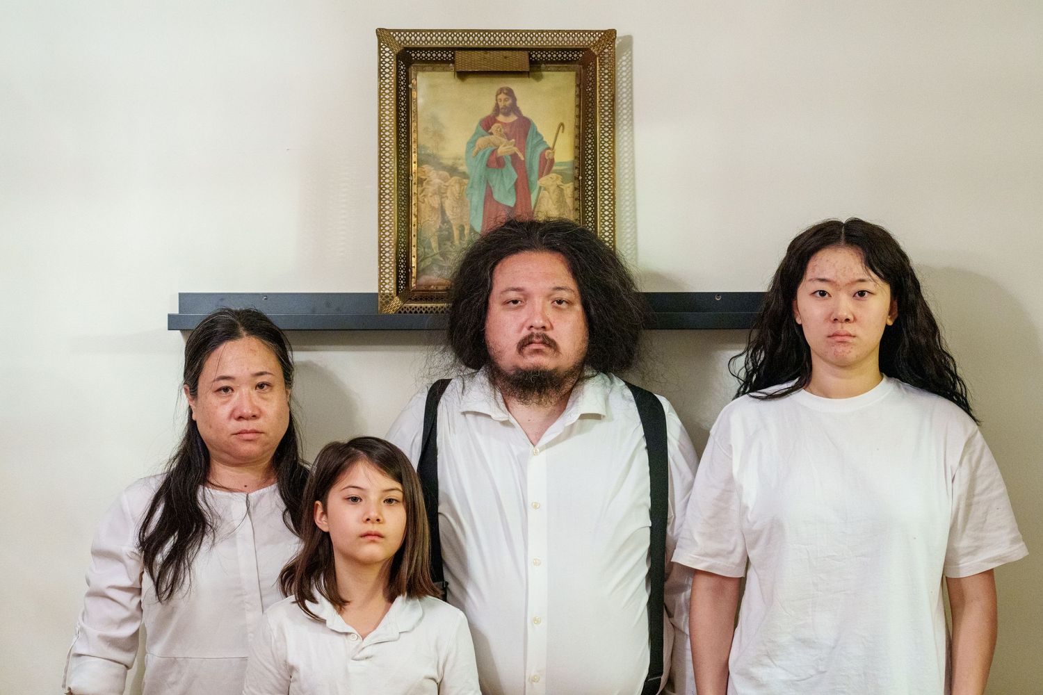 Group photo of people standing against white wall with religious artwork.