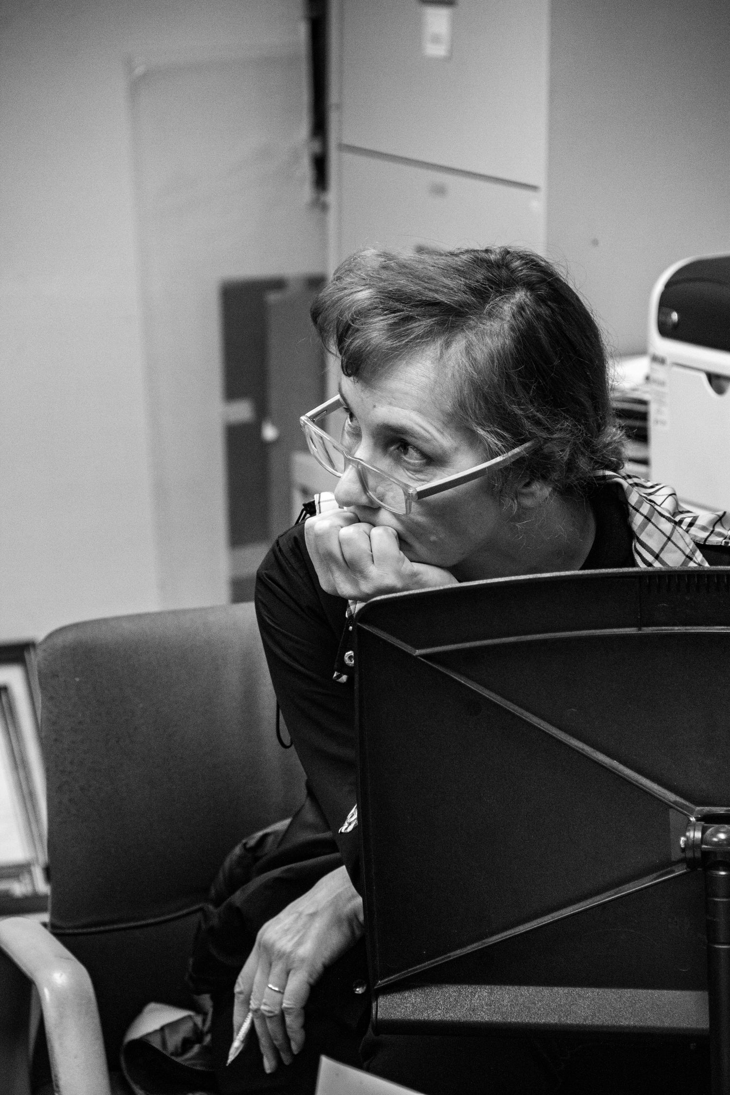 A black and white photo sequence shows someone resting their head on a dark office chair in a dimly lit room.