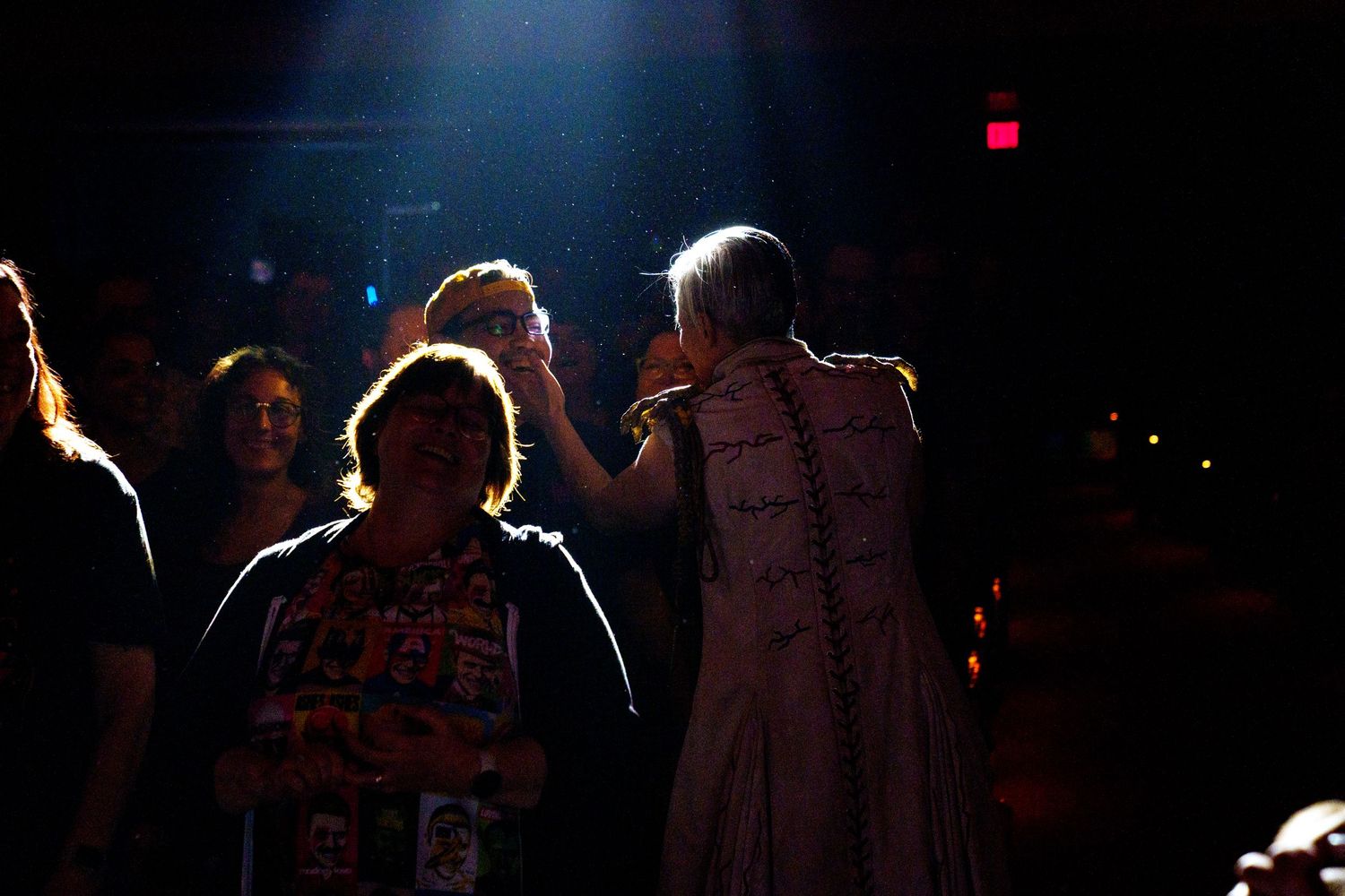 Concert scene with performers silhouetted against dark background with stage lighting.