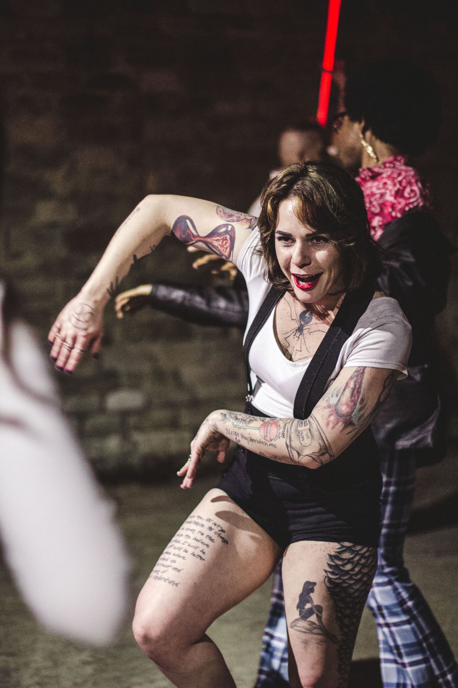 Energetic dancer with tattoos performs in casual outfit during show.