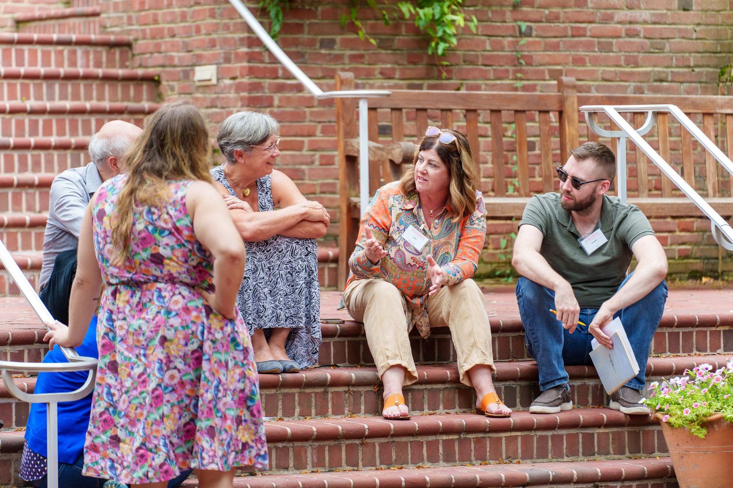 Group of people sitting on brick steps during an outdoor gathering.