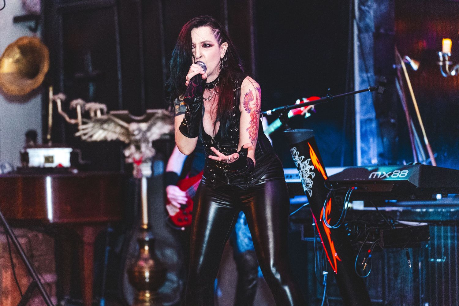 Live music performance on stage with musicians playing instruments under dramatic blue and red lighting effects.