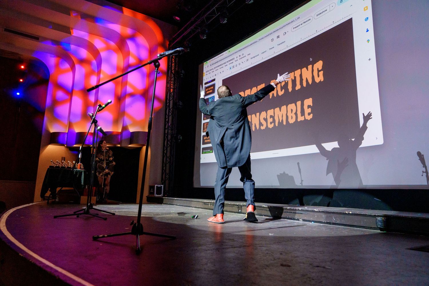 Large projection screen displaying presentation content with colored lighting effects.