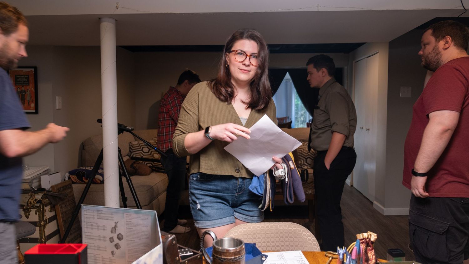 Film crew members gathered in a basement setting reviewing production materials.
