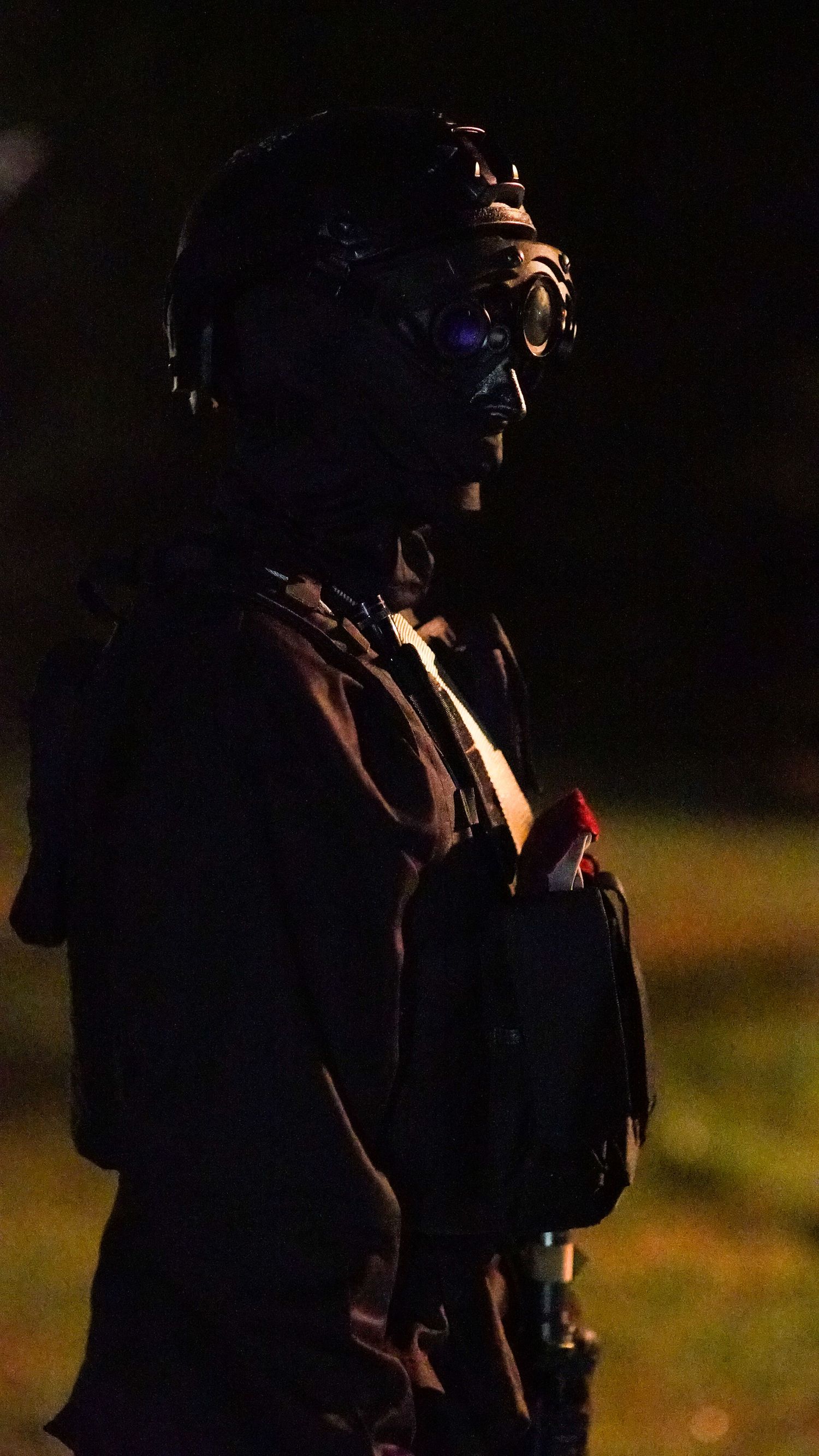 Shadowy figures in tactical gear photographed at night with minimal lighting.