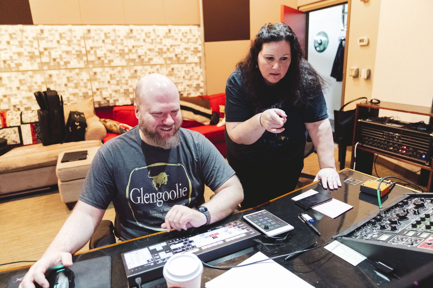 Two people reviewing materials at a table with recording equipment.
