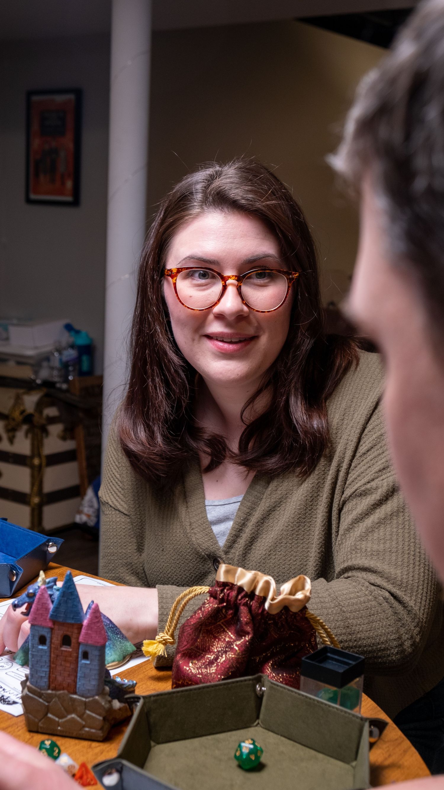 Person sits at table with miniature buildings and gaming pieces during tabletop roleplaying session.