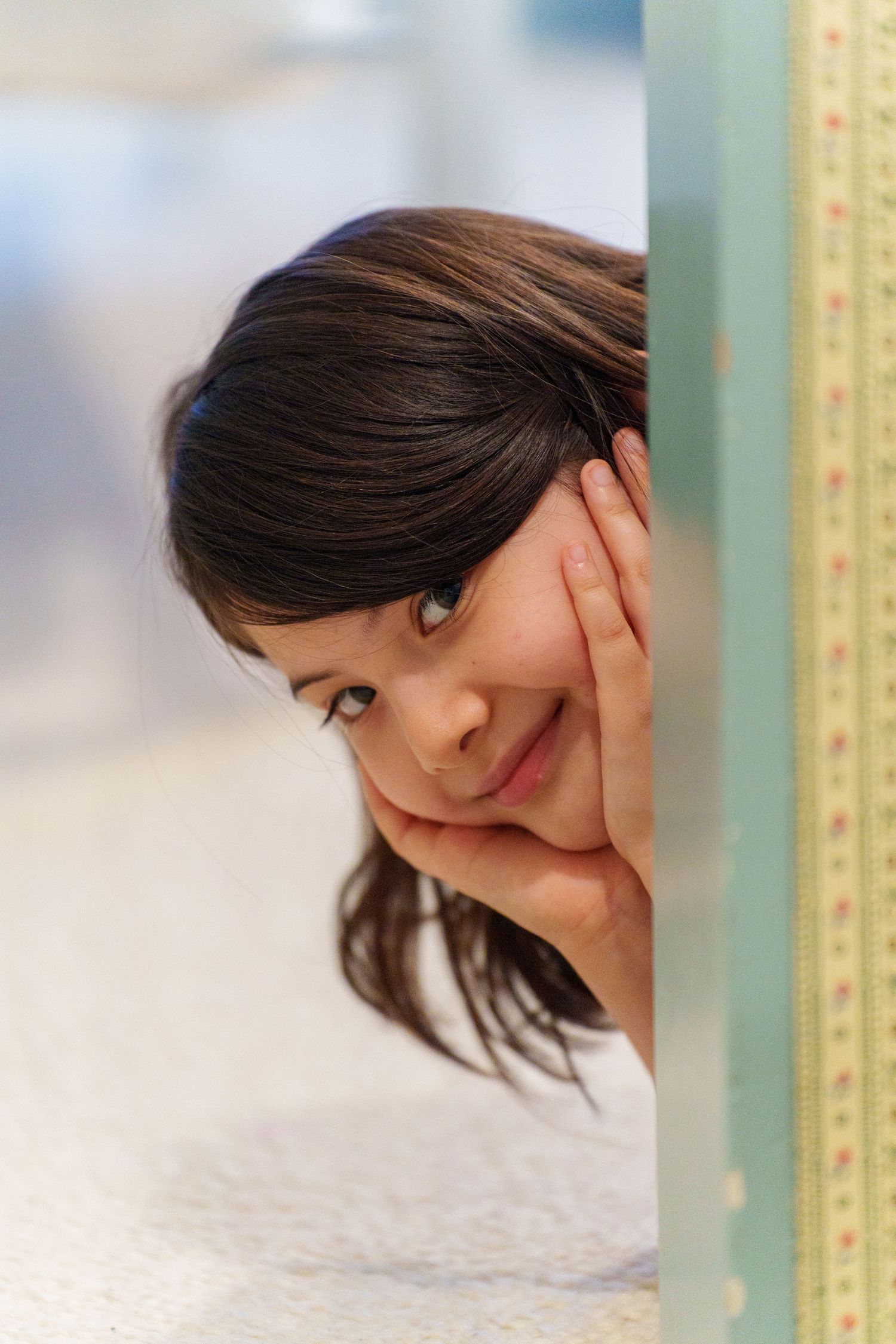 A playful pose behind a measuring tape or ruler against a light background.