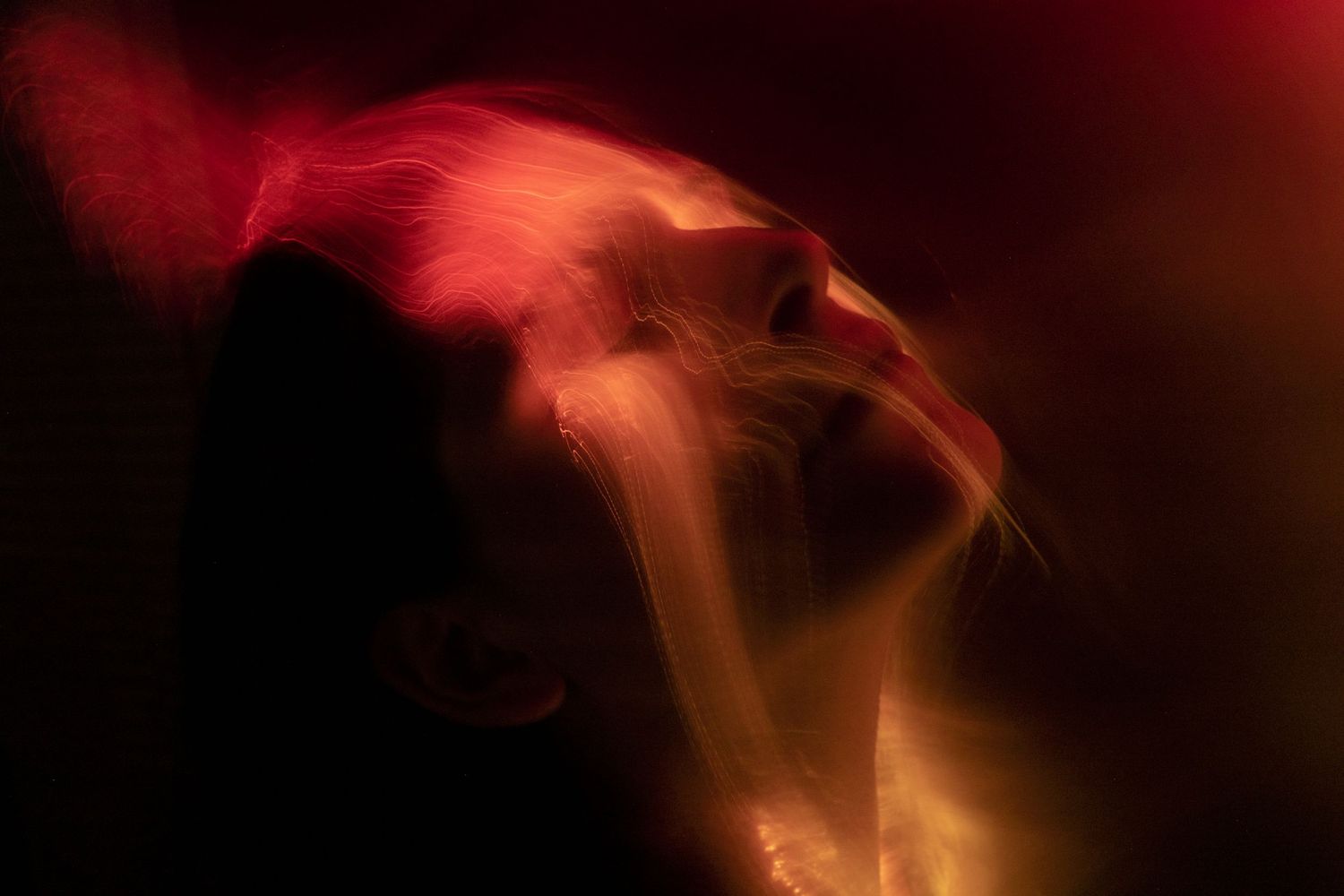 Red and orange light trails create fiery abstract patterns in darkness.