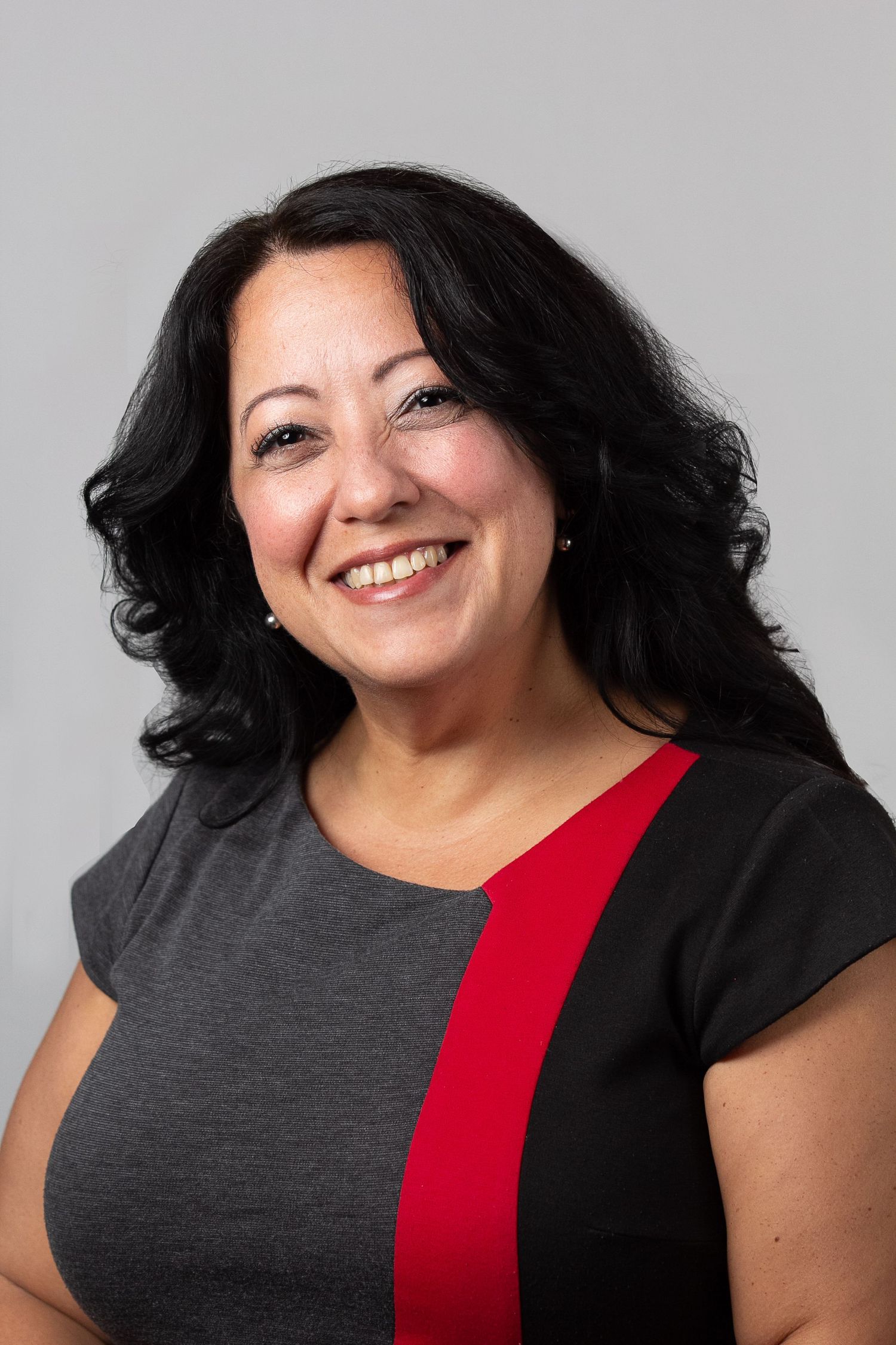 A series of headshots showing a person in a grey dress with red accent smiling against a white background.
