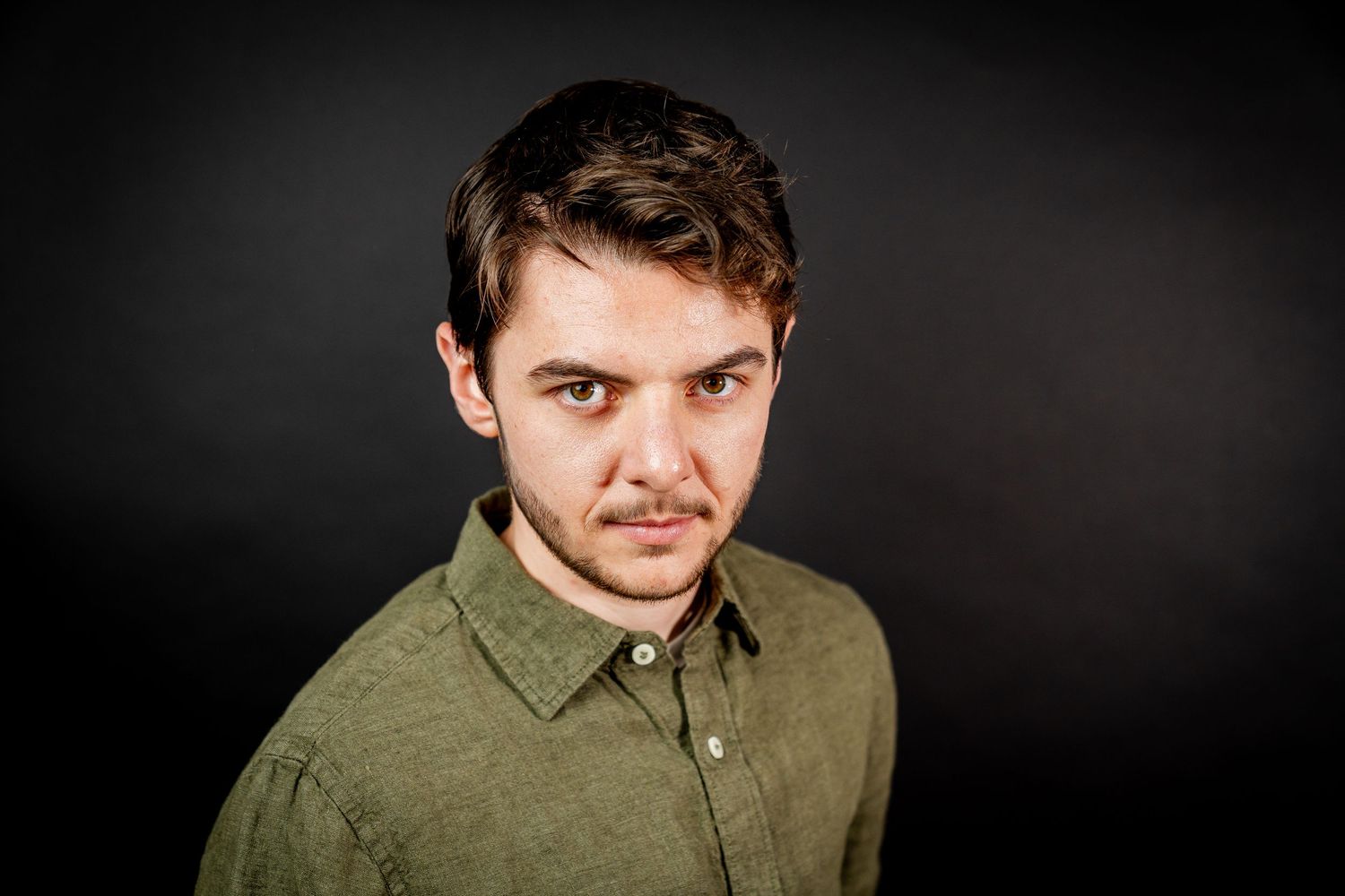 A person wearing an olive green button-down shirt poses in front of a dark background in a series of photos.