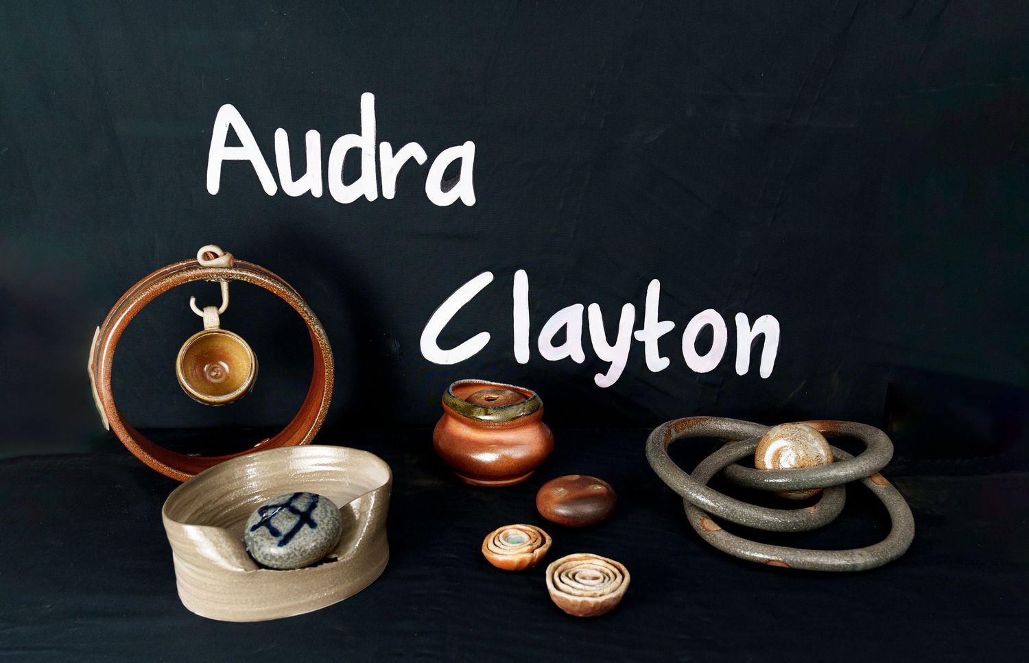 A collection of handcrafted ceramic jewelry pieces including earrings and pendants displayed on a dark background.