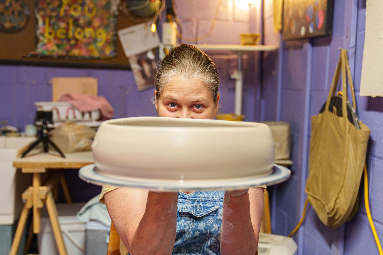 A pottery wheel spins as hands shape clay into a bowl form during a ceramic making demonstration.